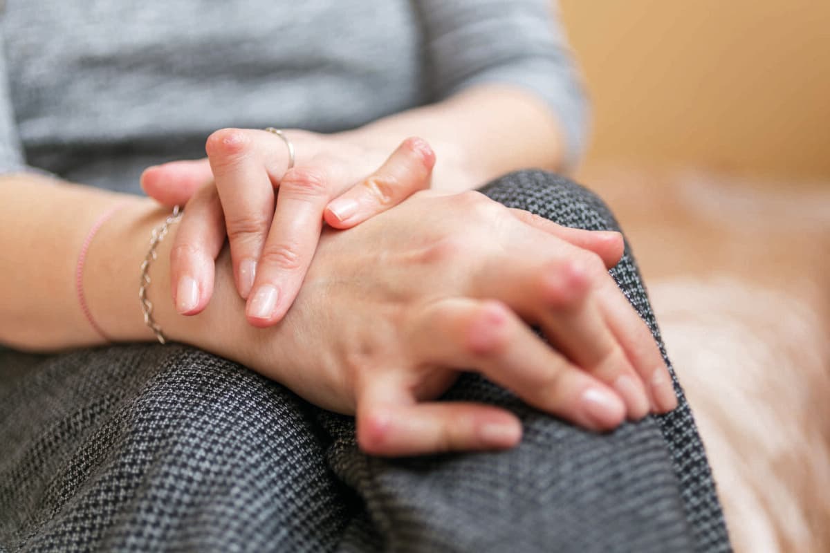 Junge Frau mit rheumatoider Arthritis ruht sich im Sitzen aus