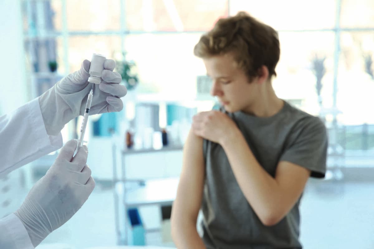 Hände des Arztes bereiten sich auf die Impfung vor und verschwommener Patient im Hintergrund
