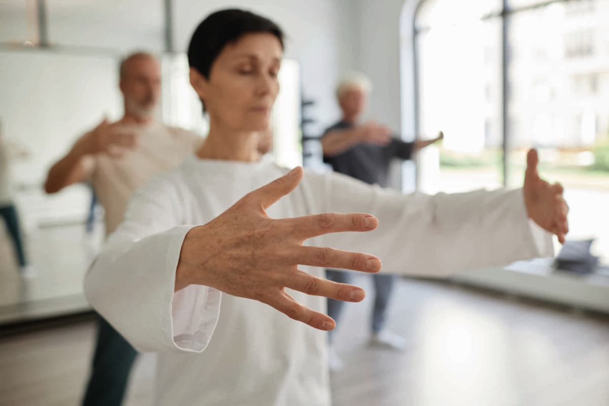 Mittlere Aufnahme mit Fokus auf die Hand einer älteren Studentin, die im Fitnessstudio Qigong-Konzentrationsübungen macht