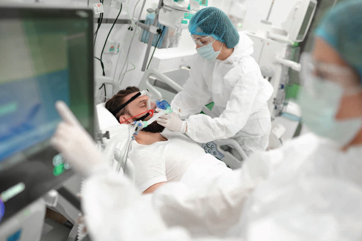 Healthcare worker in full protective gear adjusts breathing mask