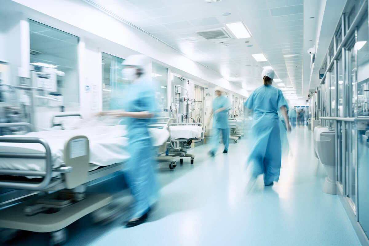 Long exposure blurred motion of medical doctors and nurses in a hospital ward wearing blue aprons, walking down a corridor – Generative AI
