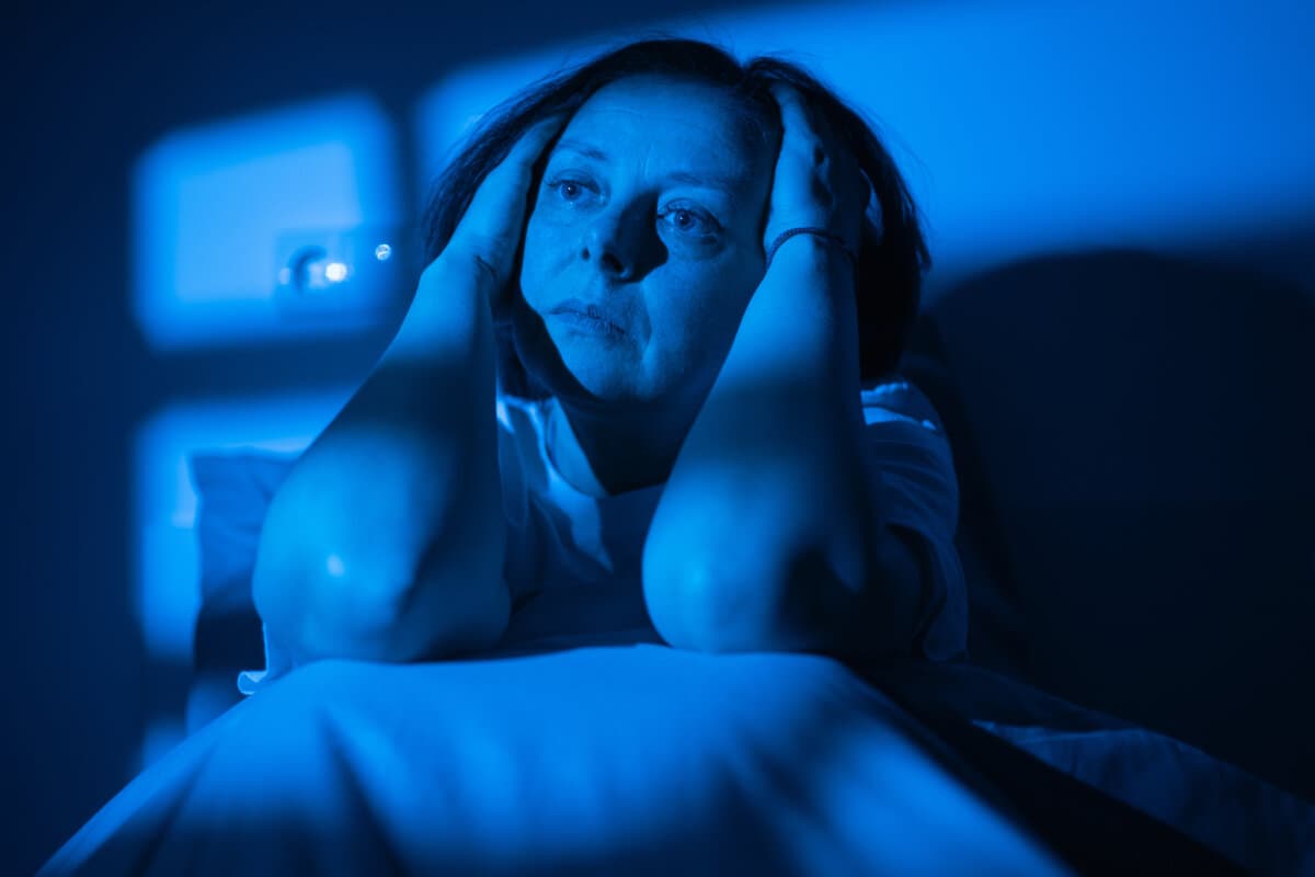 Stressed woman in bed suffering from migraine and insomnia, female feeling headache and depression during sleepless night at