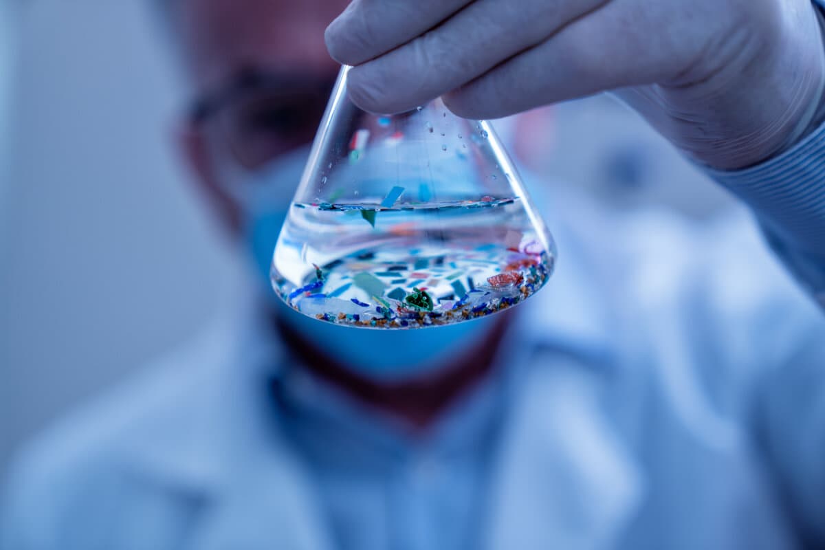 Scientist examining microplastic particles in a laboratory flask, studying environmental contamination